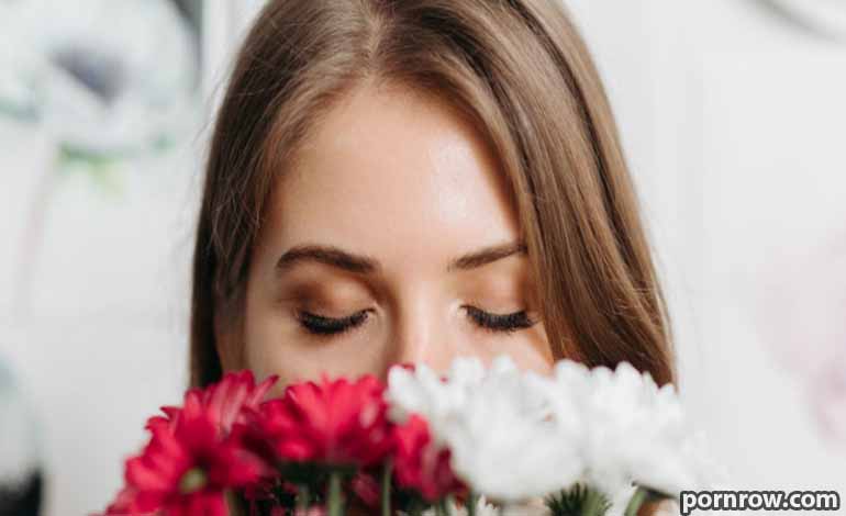 Adult Sex and Adult sex : How to Set Healthy Personal Boundaries Woman with eyes closed, smelling a bouquet of red and white flowers.